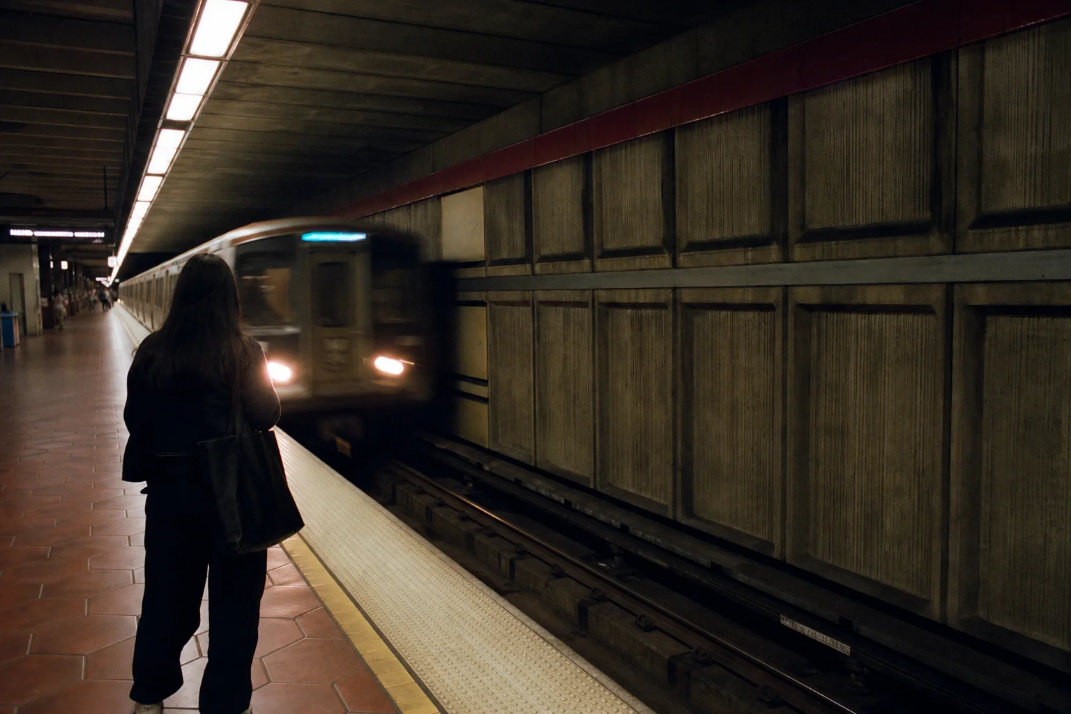 A Metro train arriving beside a waiting passenger
